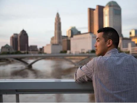 A man looking out over the river with downtown Columbus in the background