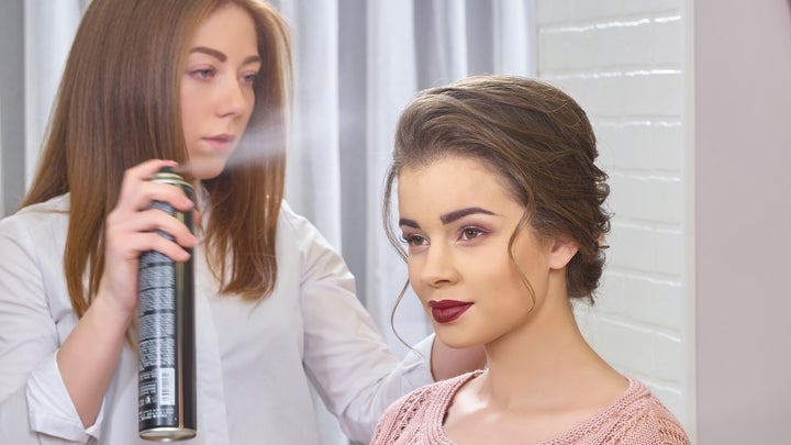 hair dresser using spray on her client's hair