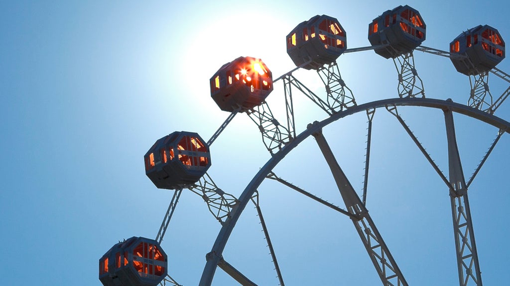 sun shining through a ferris wheel at a festival