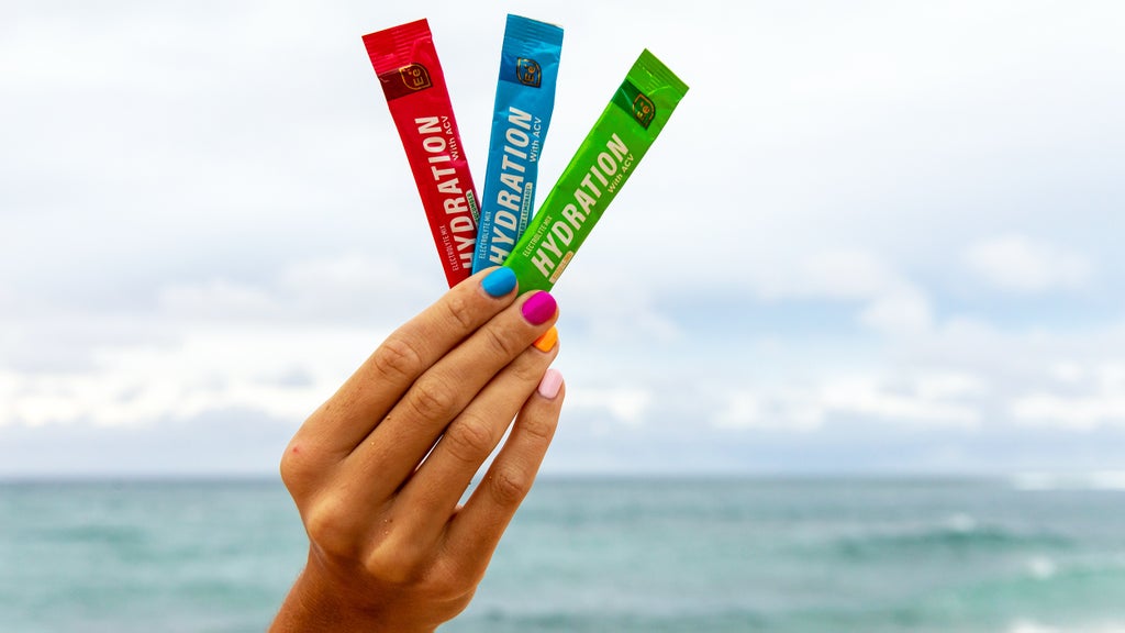 woman holding packages of three Essential elements Hydration flavors