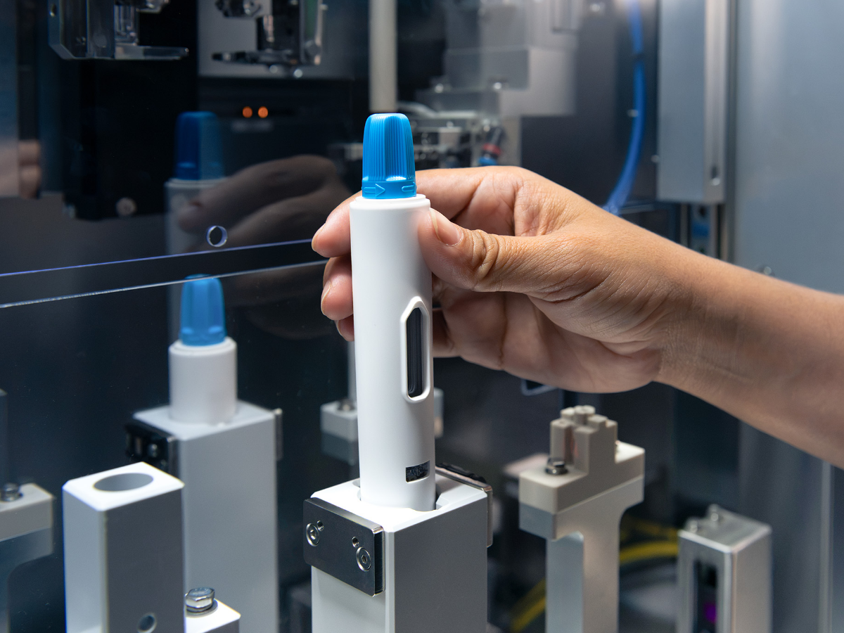 Hand placing a Magnitude autoinjector into automated manufacturing equipment