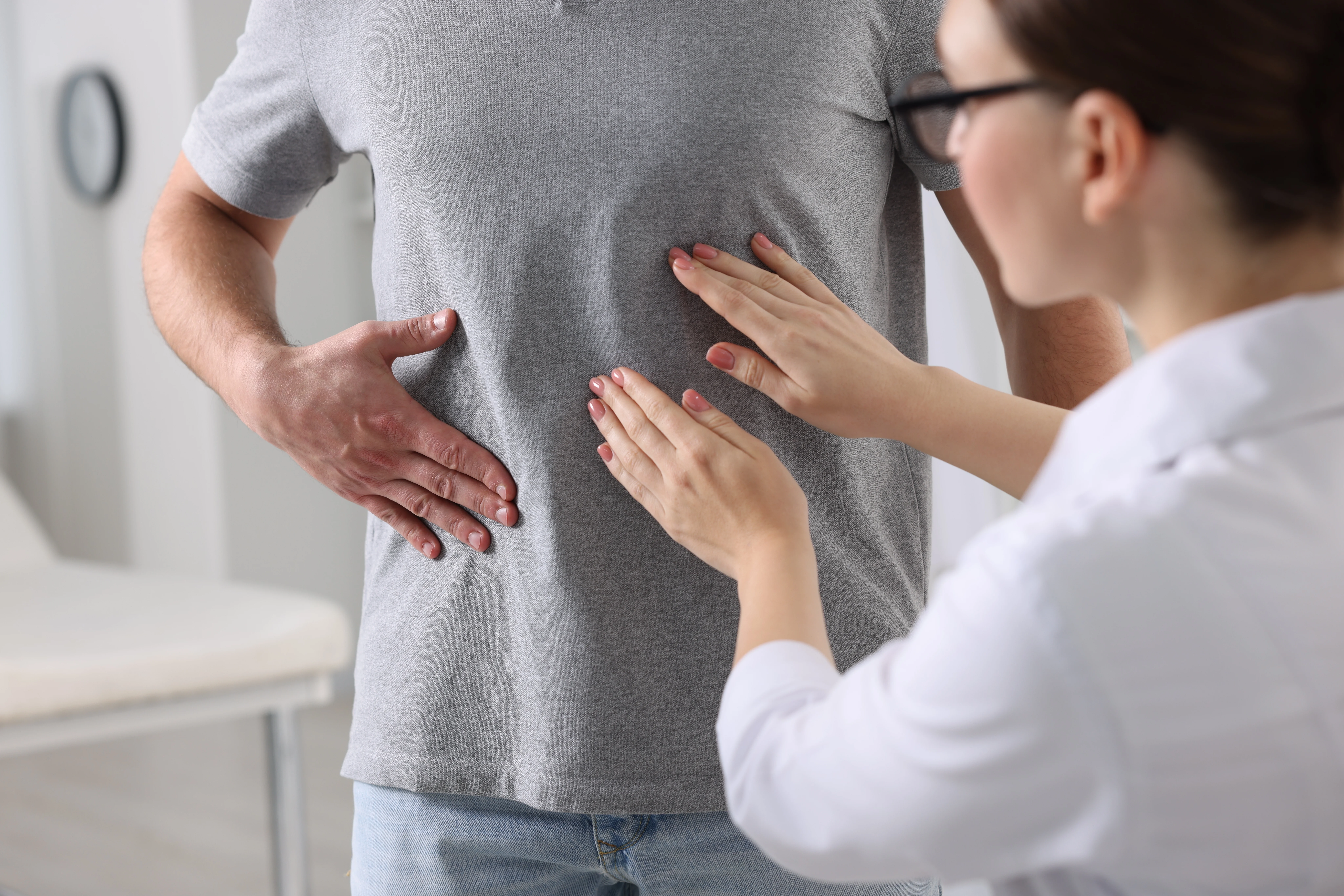 A doctor is examining a patient 's stomach in a hospital