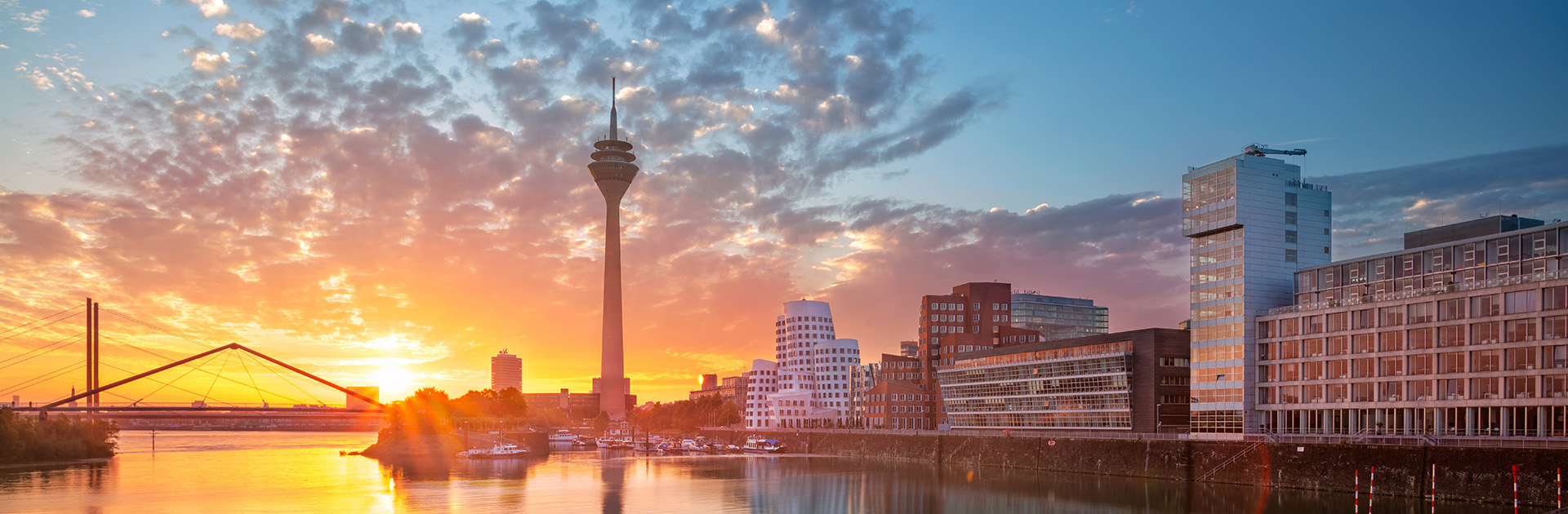 Skyline view of Düsseldorf, Germany, with high-rise buildings and a bridge over a river. Düsseldorf is where the K 2025 Plastics Fair is held, and SHL Advantec will showcase its advanced manufacturing tooling and automation solutions at Hall 12, Booth C35-03.