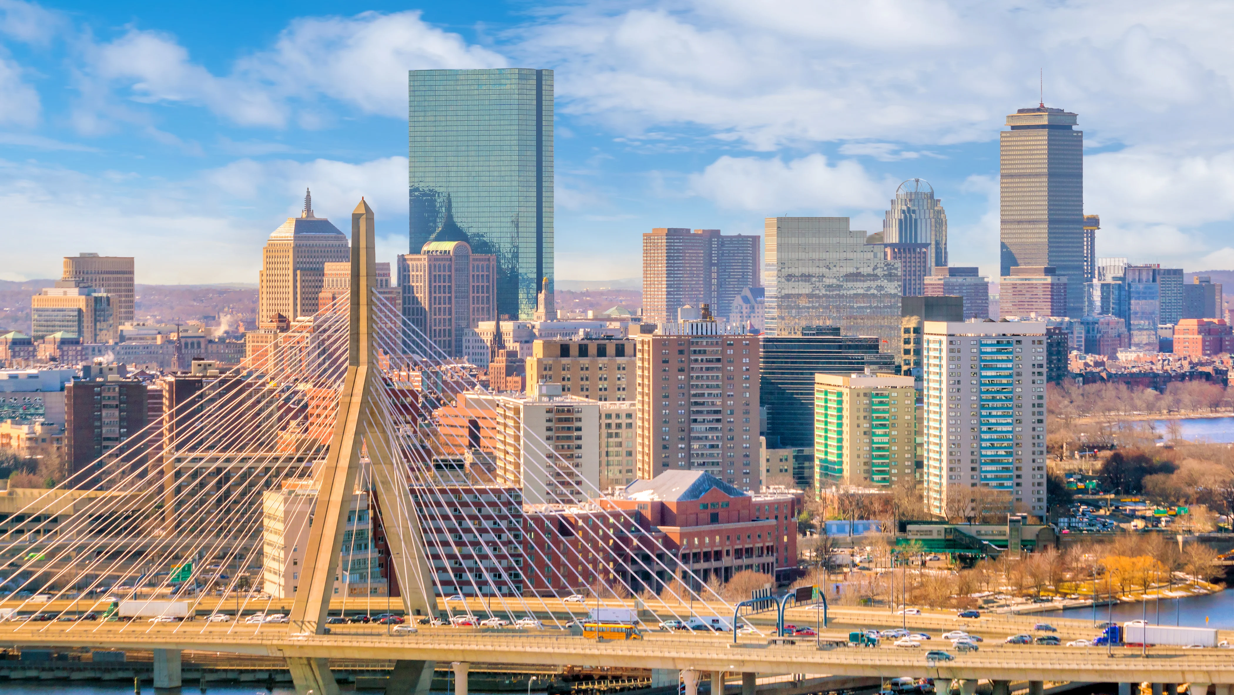 View of the Boston skyline and waterfront, featuring high-rise buildings under a blue sky. SHL Advantec will join SHL Medical at PODD 2026, highlighting drug delivery device manufacturing, autoinjector assembly, and medical device automation.