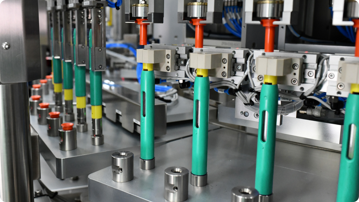 DAI autoinjector positioned vertically inside automated production equipment with red inspection lighting.