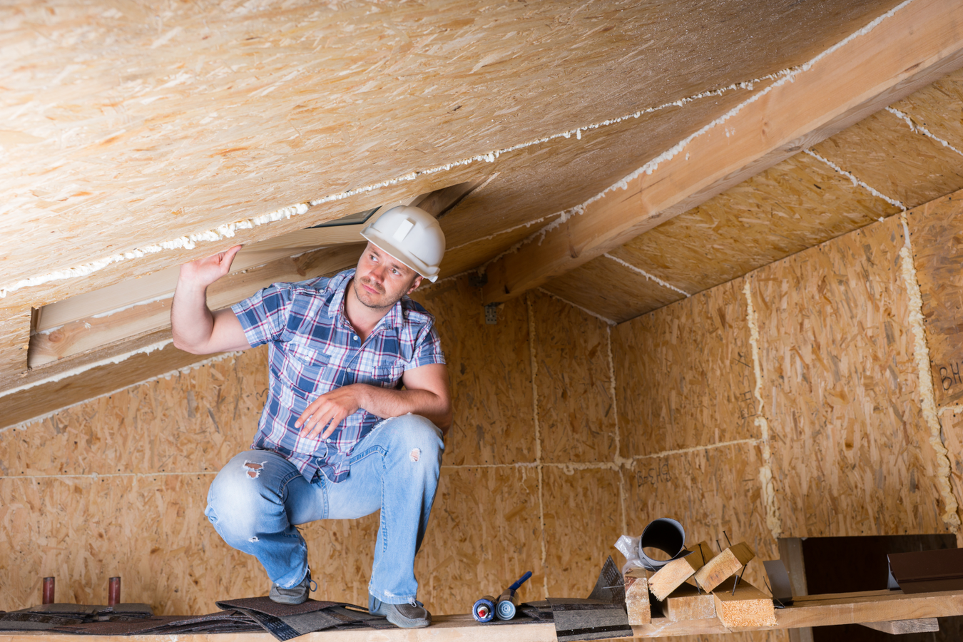 contractor with a hard hat on in an attic crawl space