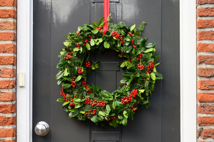 A ribbon-hung Christmas wreath on an entry door.