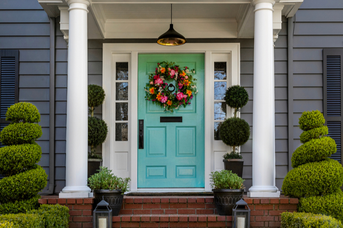 Front porch of a traditional home with aqua-colored front door and gray exterior siding