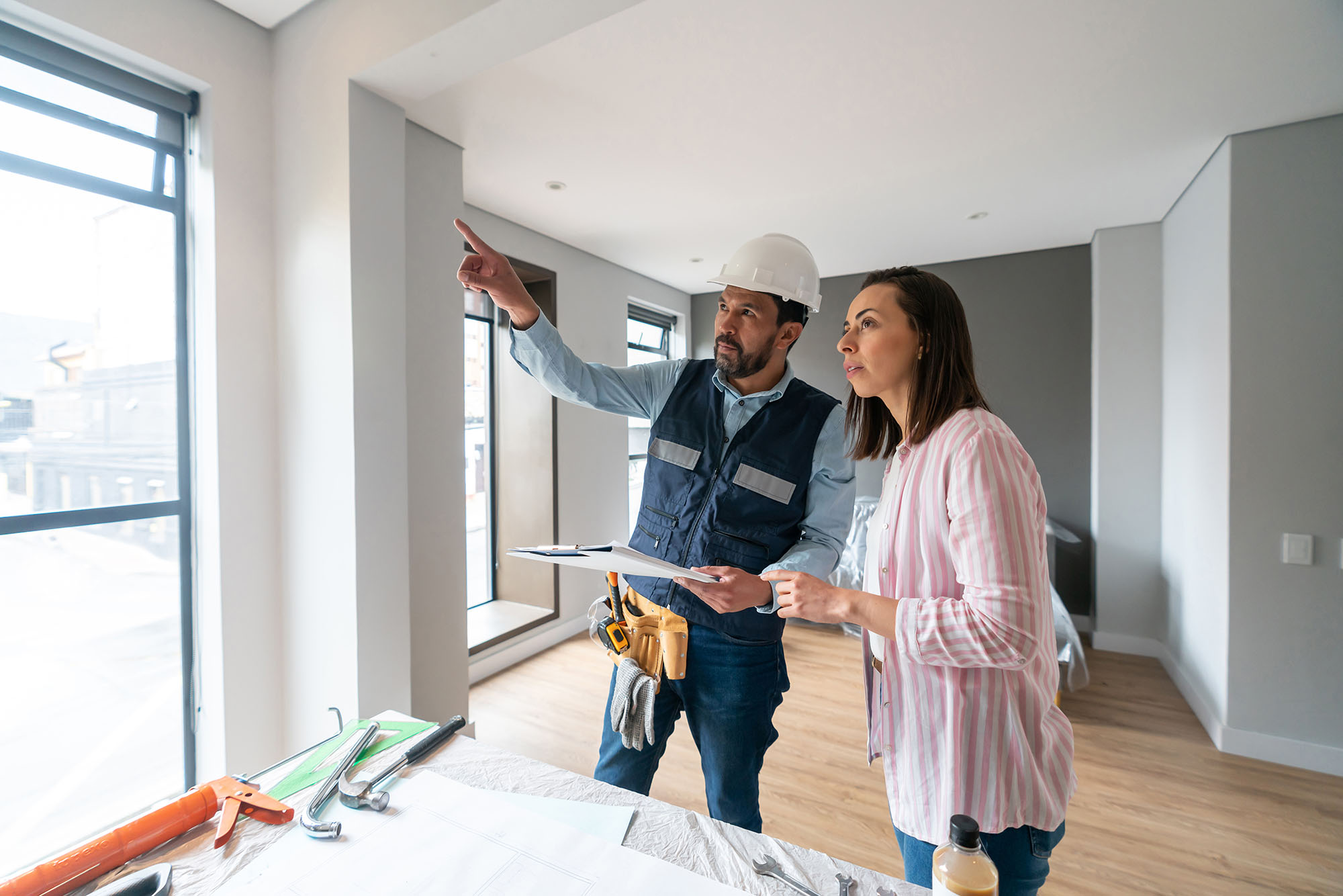 Window replacement contractor seemingly explaining to a woman details of the window replacement project