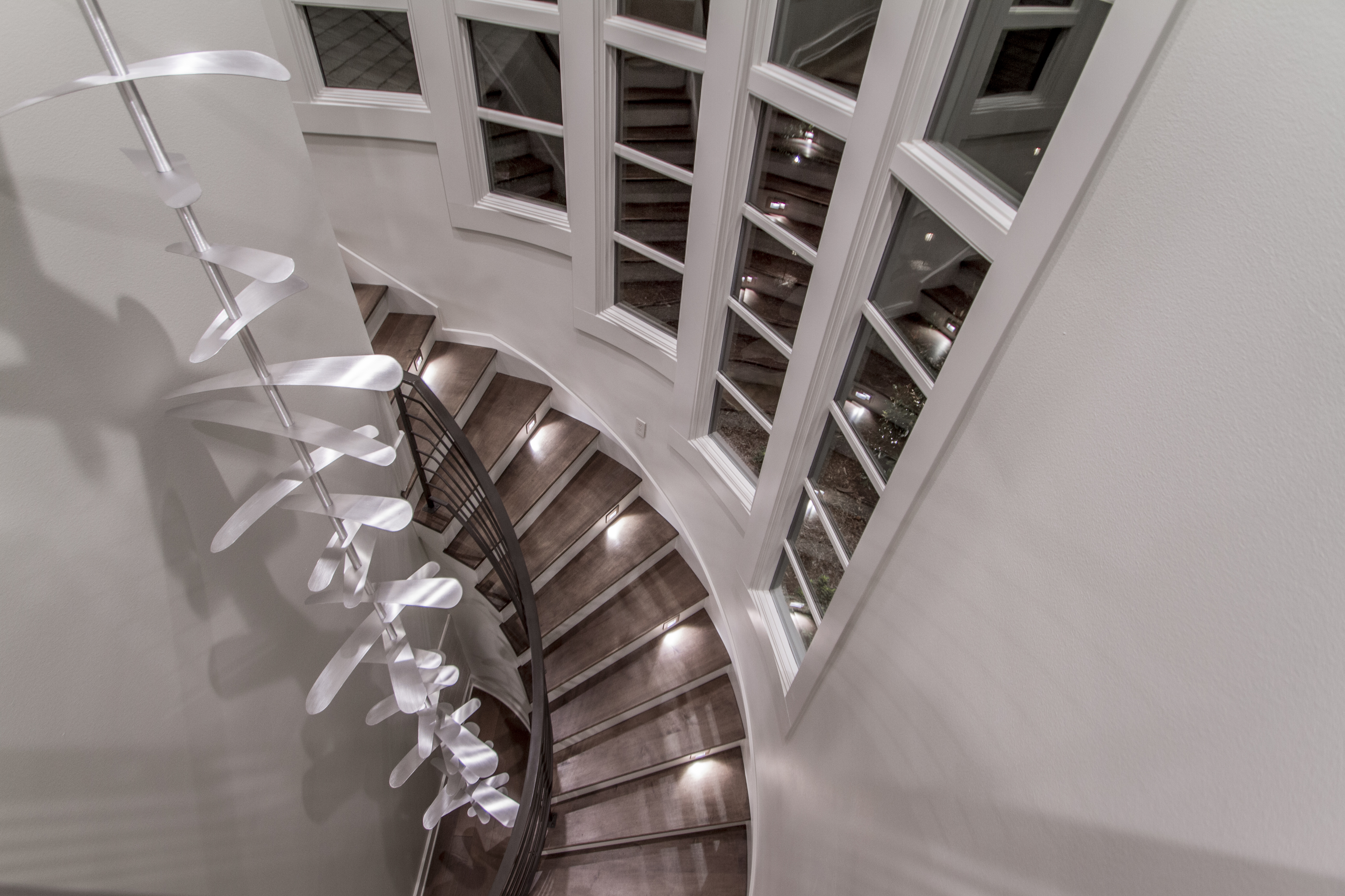 Several white interior wood-clad direct set & radius windows surrounding a staircase