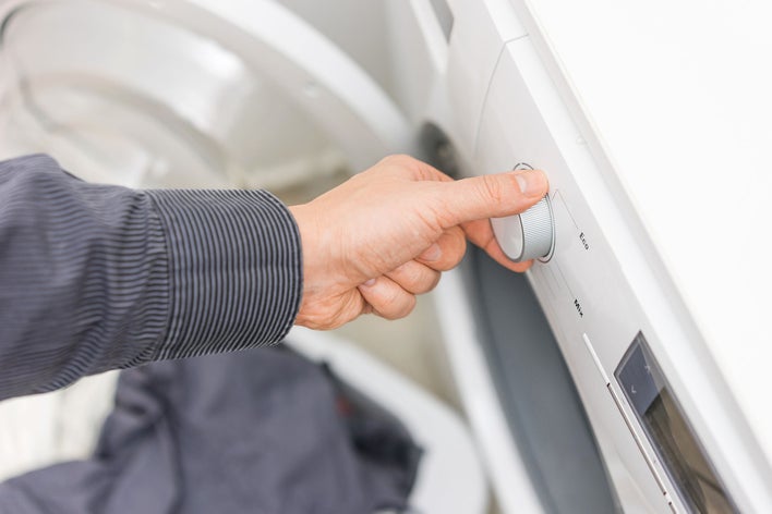 A person changing the setting on their washing machine to reduce their carbon footprint by using cold water instead of hot.
