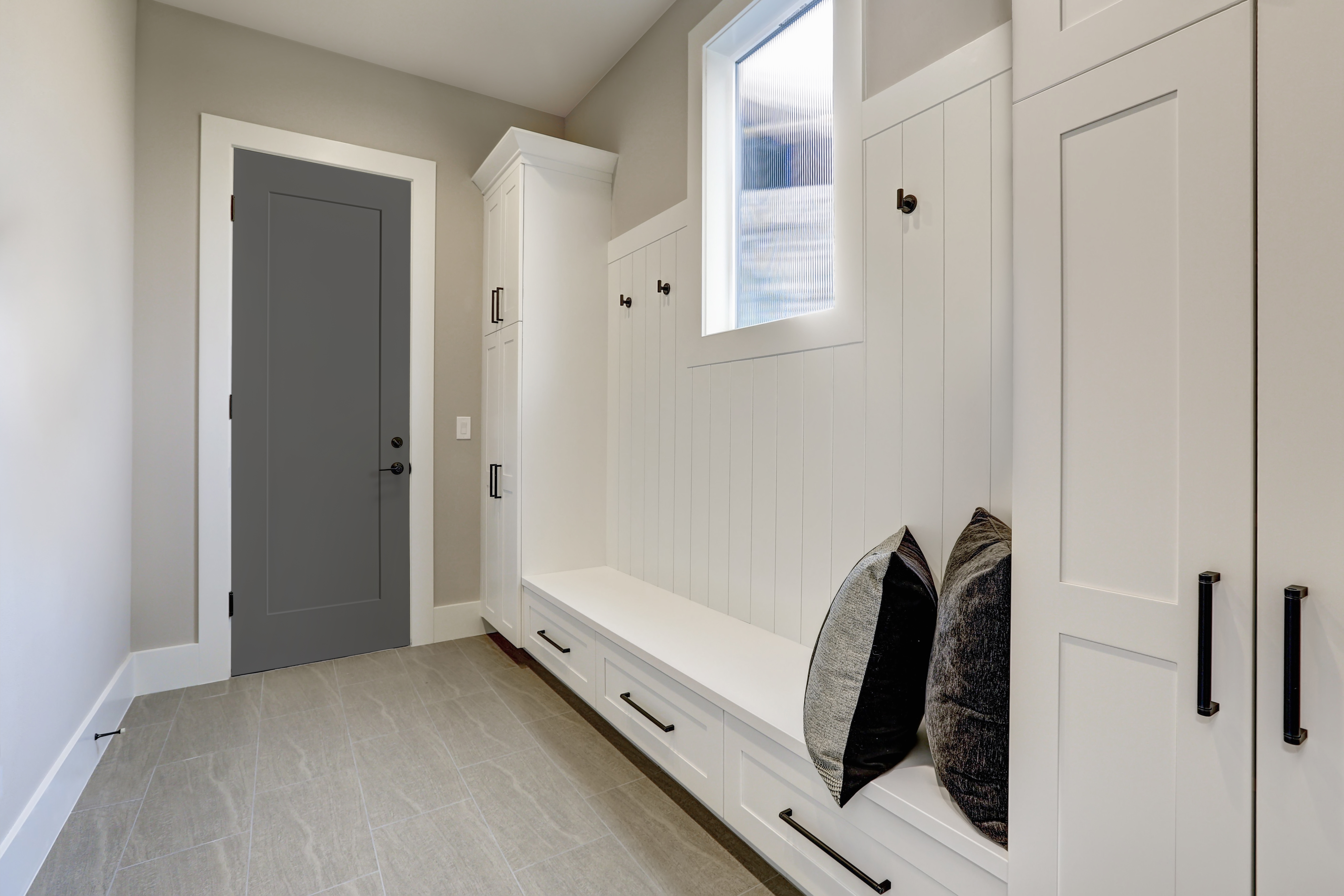 A gray 1 panel smooth steel door with a black handleset in a mudroom