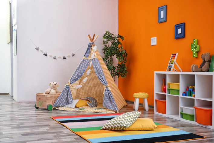 A colorful children's play space with tent and orange accent wall