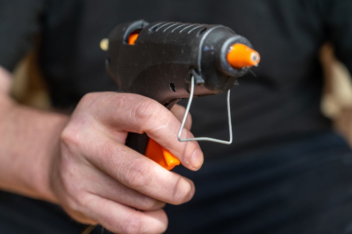 Man holding a hot glue gun for a Halloween door decorating craft.