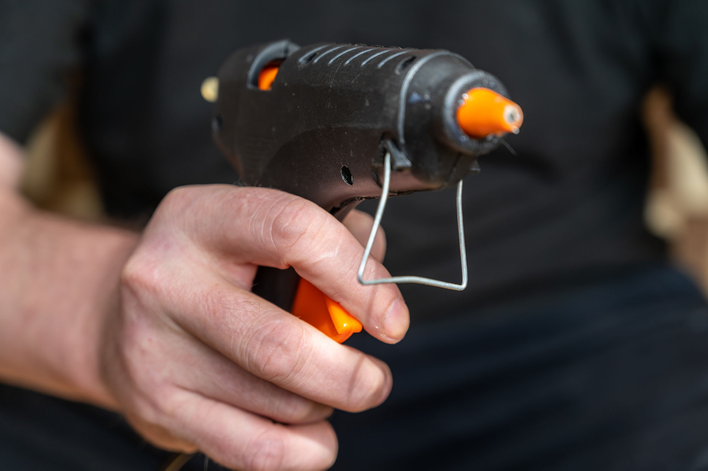 Man holding a hot glue gun for a Halloween door decorating craft.