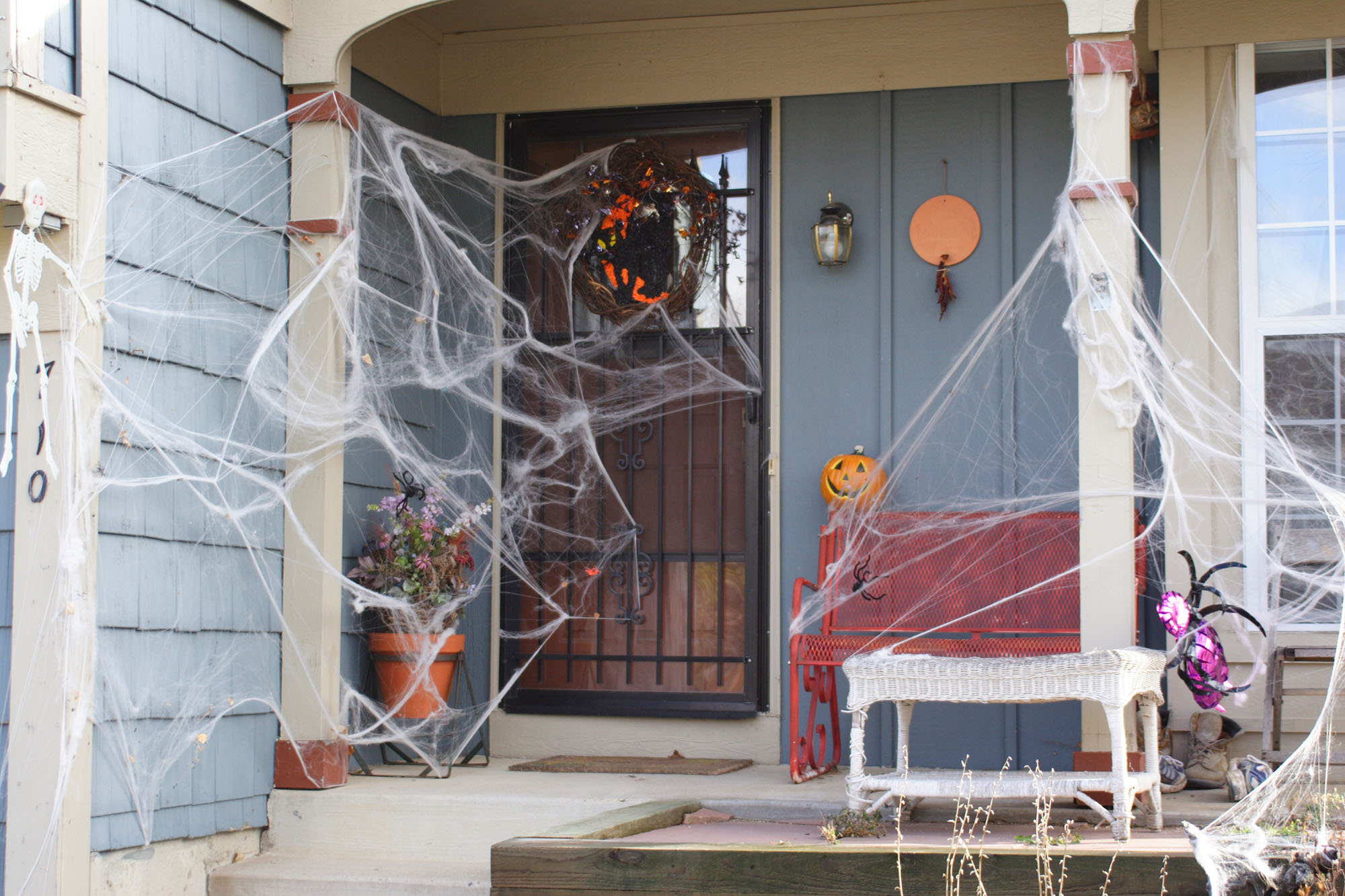 Halloween door decorations on the entryway of a home including large spiderwebs