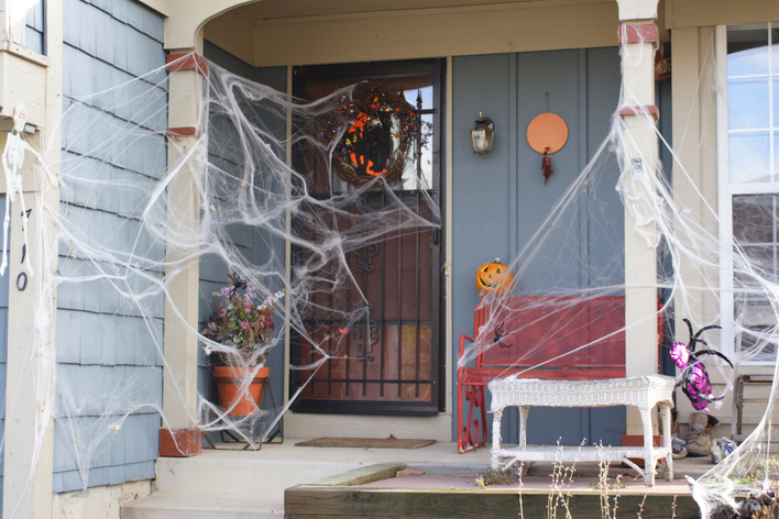 Halloween door decorations on the entryway of a home including large spiderwebs