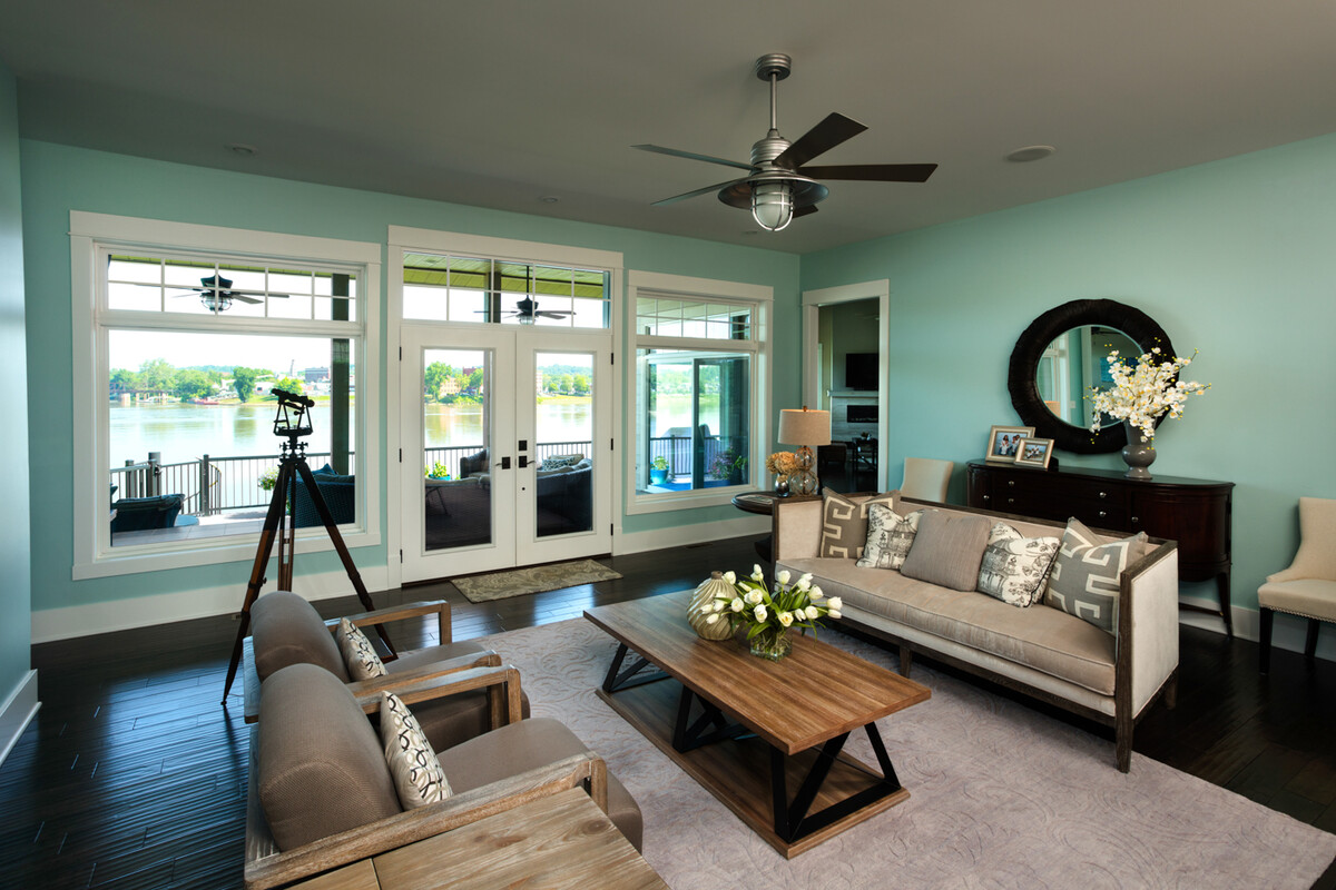 picture windows above hinged patio doors in a modern living room with teal walls and waterfront view