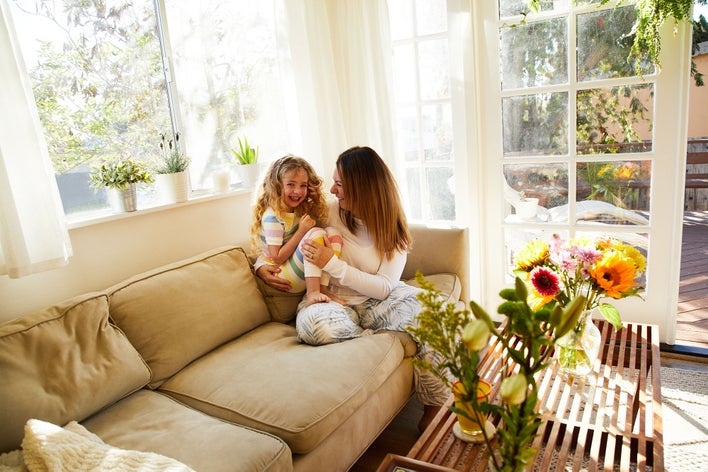 Woman and daughter sitting on a couch surrounded by window replacements.