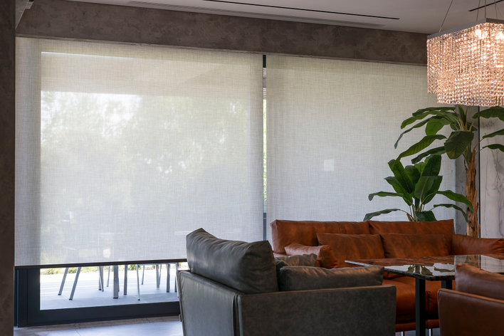 Roller shades over large windows between a living room and patio make for pet-proof window treatments.