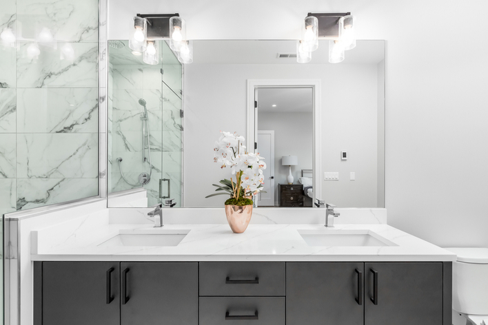 A modern white bathroom with marble tile and white countertops A modern white bathroom with marble tile and white countertops