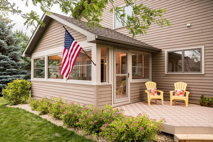 A retractable screen storm door is used as the entrance to a sunroom from the back patio