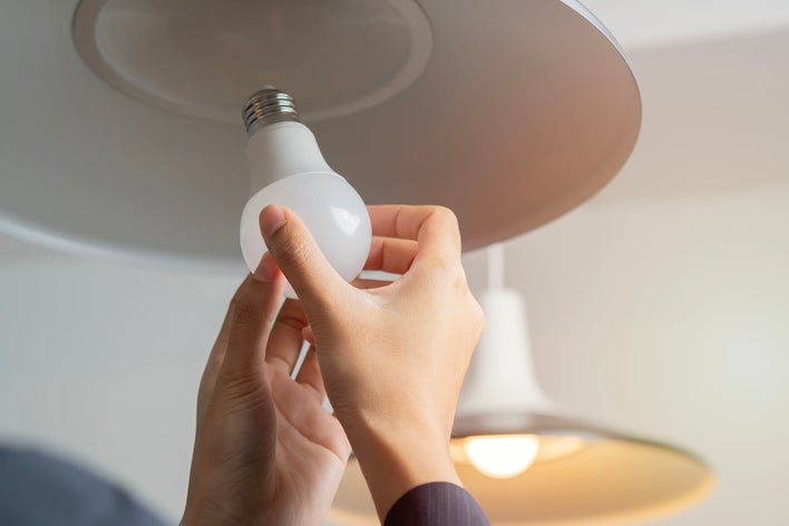 A person installing an LED bulb, one of the easiest ways to reduce your carbon footprint.