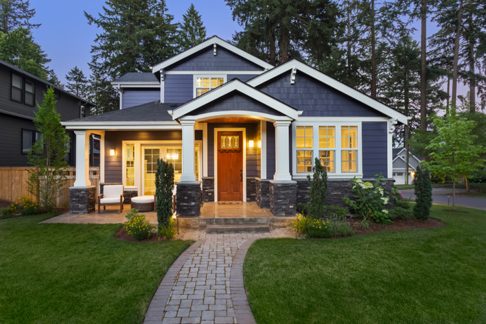 A navy blue and stone craftsman-style home with a woodgrain entry door