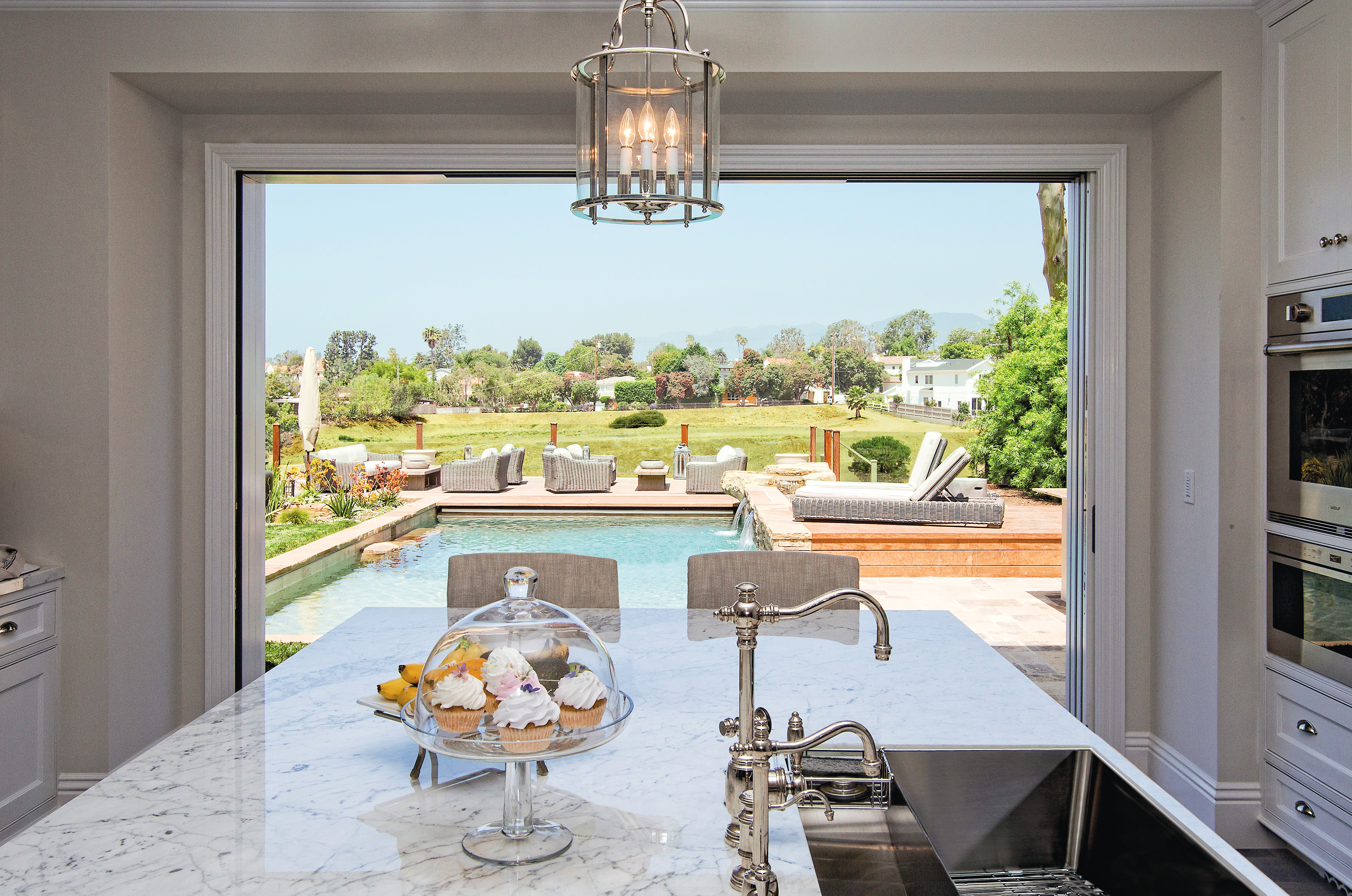 A kitchen with a fully opened multi-slide patio door connecting to a porch and pool area