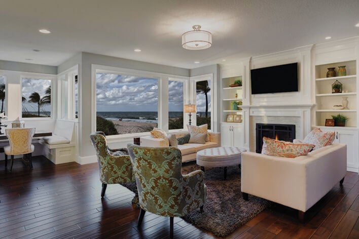 A living area in a beachfront home with large windows that a homeowner will need to prepare for hurricane season A living area in a beachfront home with large windows that a homeowner will need to prepare for hurricane season