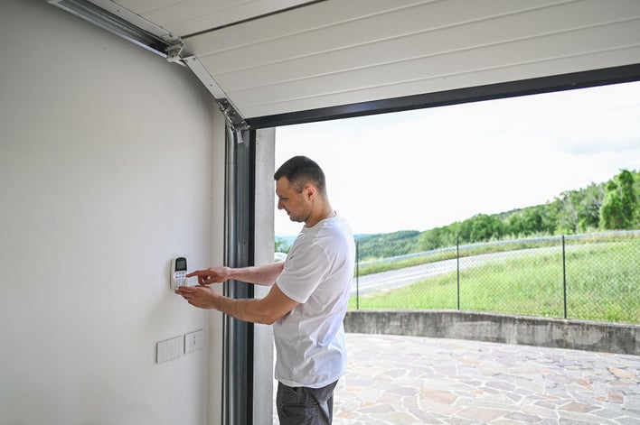 Man in a garage of new home checking the security system.