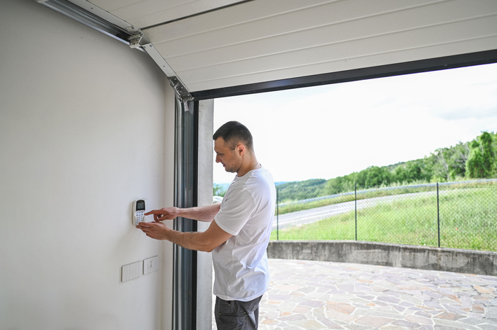 Man in a garage of new home checking the security system.