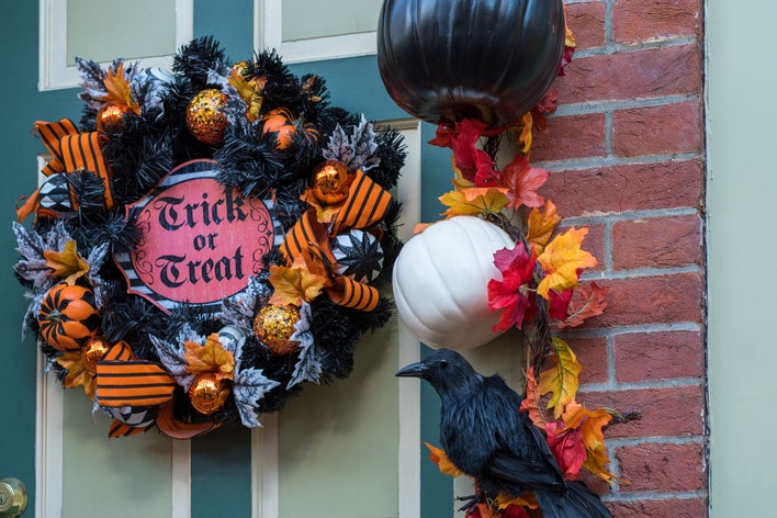 Crow-themed Halloween wreath dressed on a front door that reads ”Trick or Treat.”