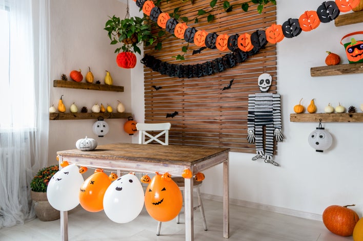 A room with a small brown wooden table and various Halloween décor