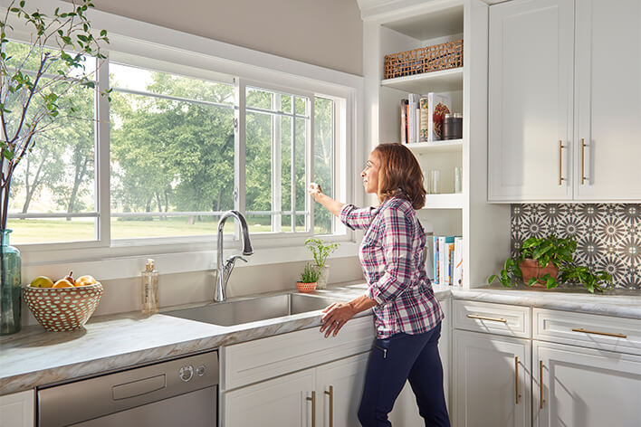 Woman opening a sliding window above her kitchen sink