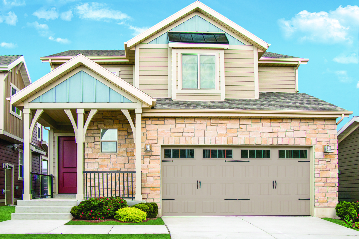 Taupe colored vertical short panel garage door with stockbridge windows and decorative hardware on a two-story home