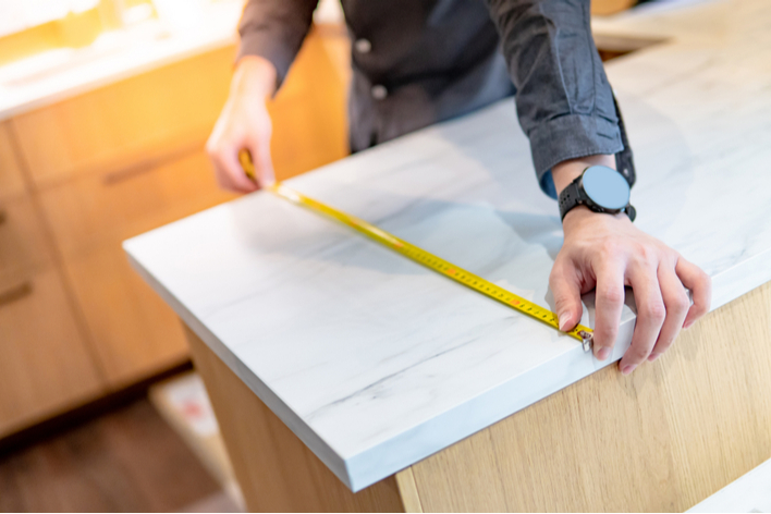 A person measuring a countertop in a kitchen