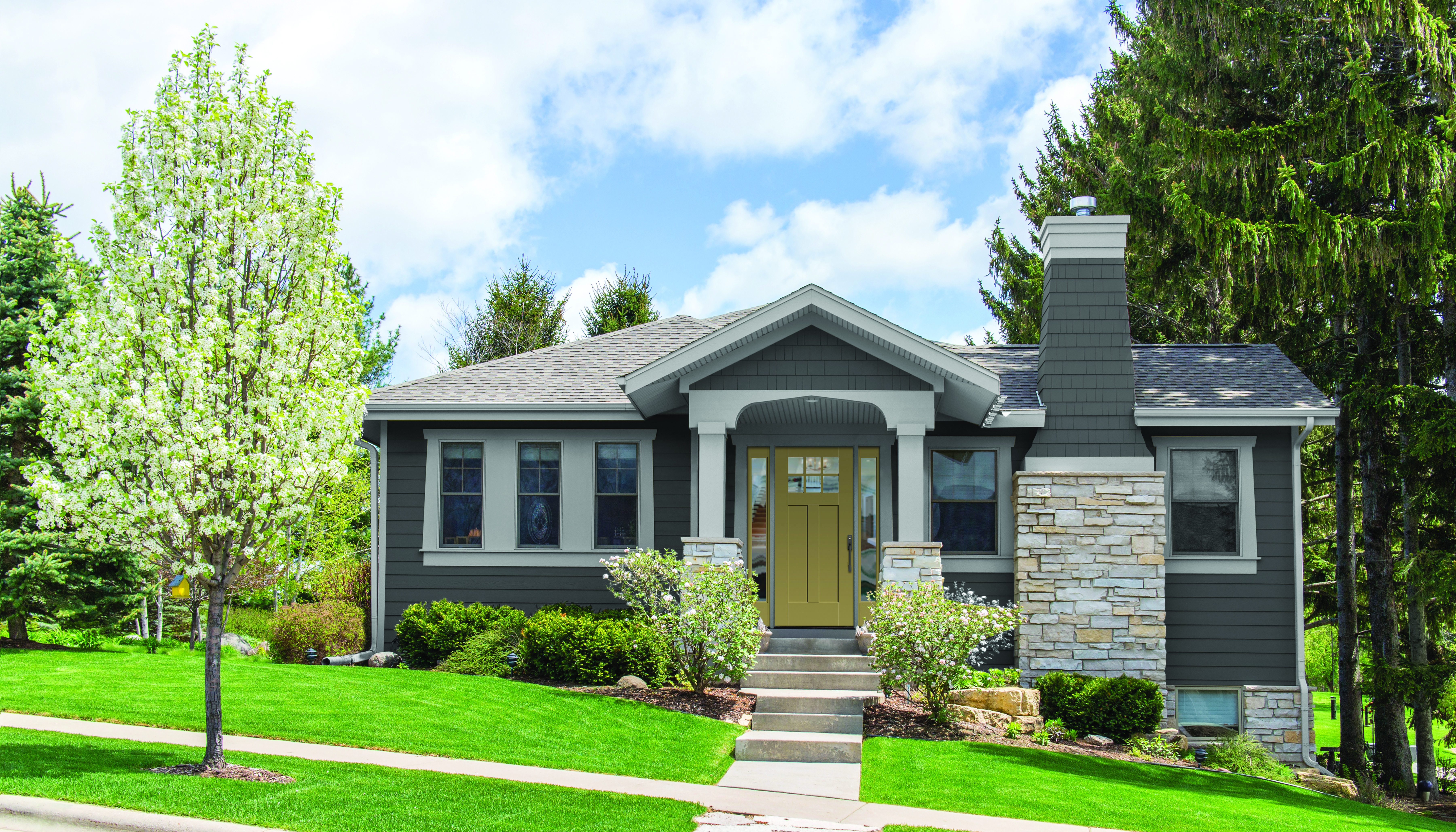 A tidy home exterior with gray siding and a yellow fiberglass front door.