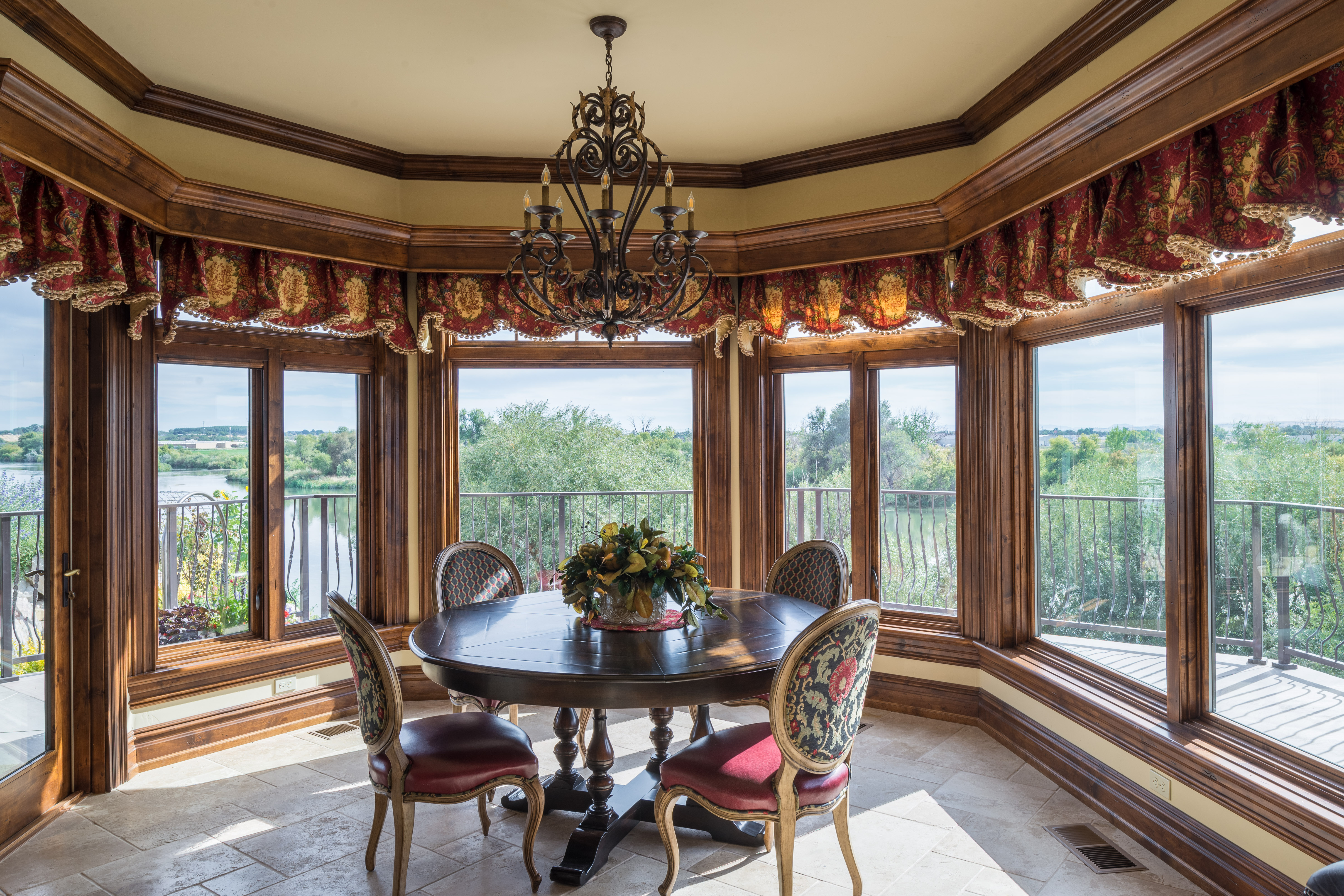 Brown wood interior wood-clad casement & awning windows in a dinning room with a deck on the outside overlooking a river