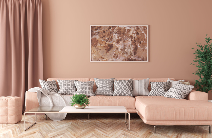 A living room sectional, art, and window treatments utilizing the 2024 Color of the Year<br>from Pantone, “Peach Fuzz”