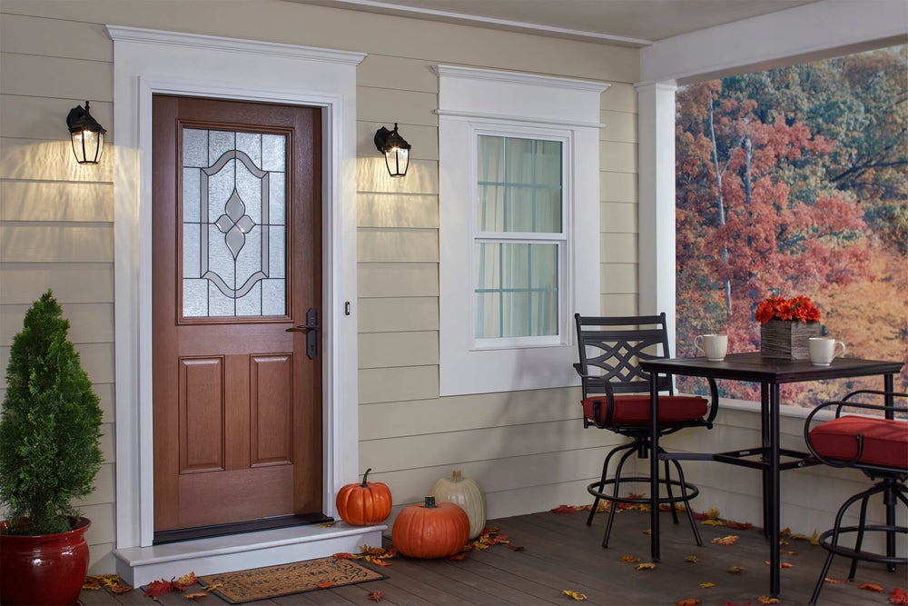 A front door with fall pumpkins sitting on the porch