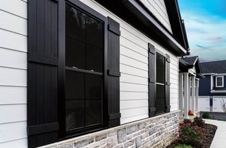 Home with Alside ASCEND Composite Cladding in Glacier White, AMI 4000 Series Charter Oak Soffit in black and black 4000 Series Windows with Exterior Decorative Window Trim.