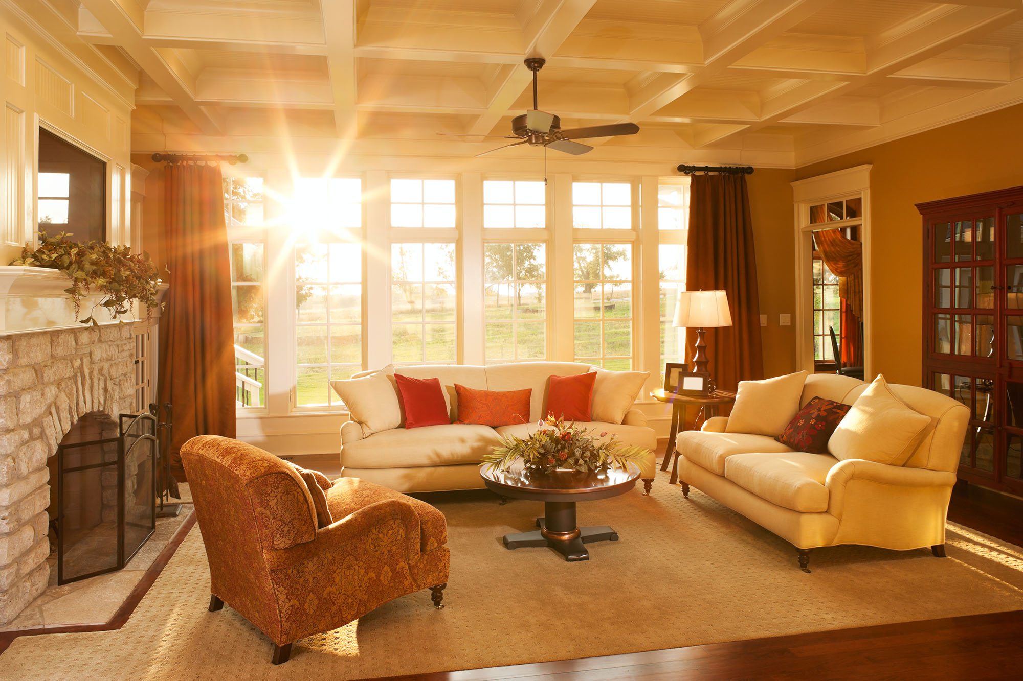 Sun shining into a living room with a couch in front of windows.