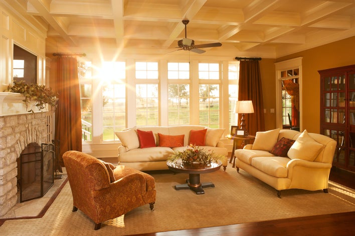 Sun shining into a living room with a couch in front of windows.