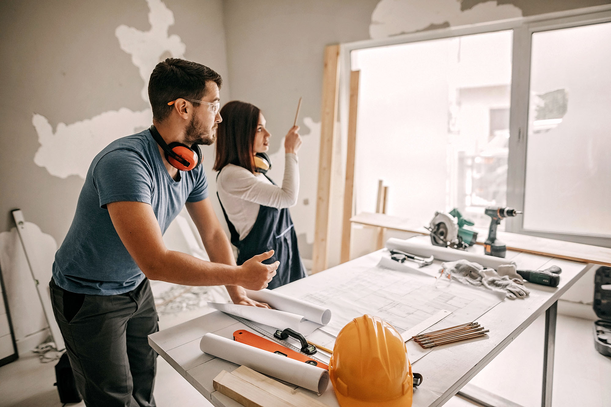 A couple planning out their DIY home remodel project surrounded by construction tools and materials.