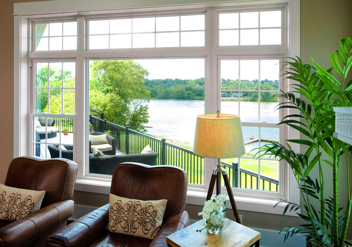 expansive picture window with colonial grille detail framing a scenic lake view from a cozy living space
