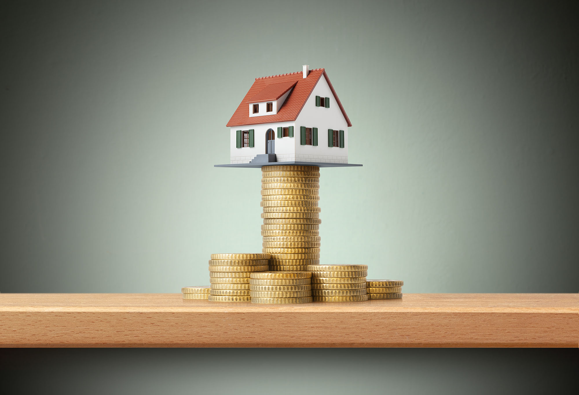 A model house atop a stack of coins meant to illustrate the financial investments of home ownership and DIY home renovations.