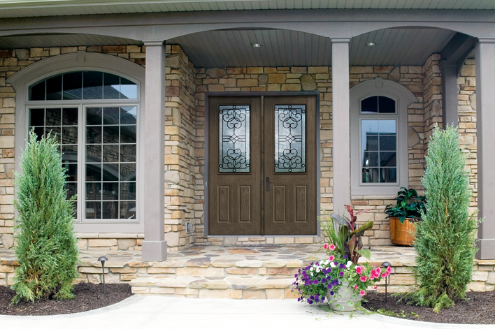 Woodgrain exterior fiberglass doors with decorative glass match the classic styling of a<br>stone-fronted house.