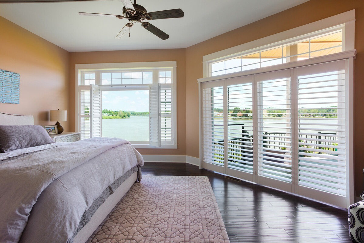bedroom with bay-style picture window surrounded by white shutters and a panoramic river view