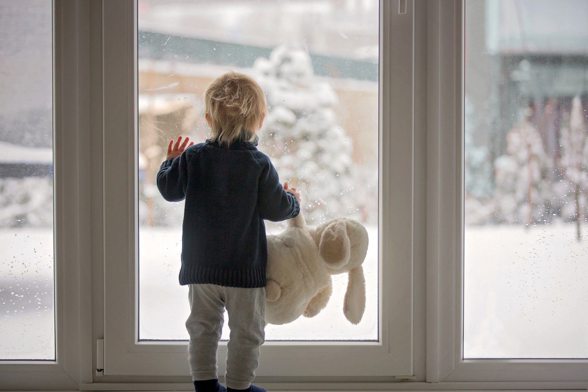 Young boy looking out of window in winter